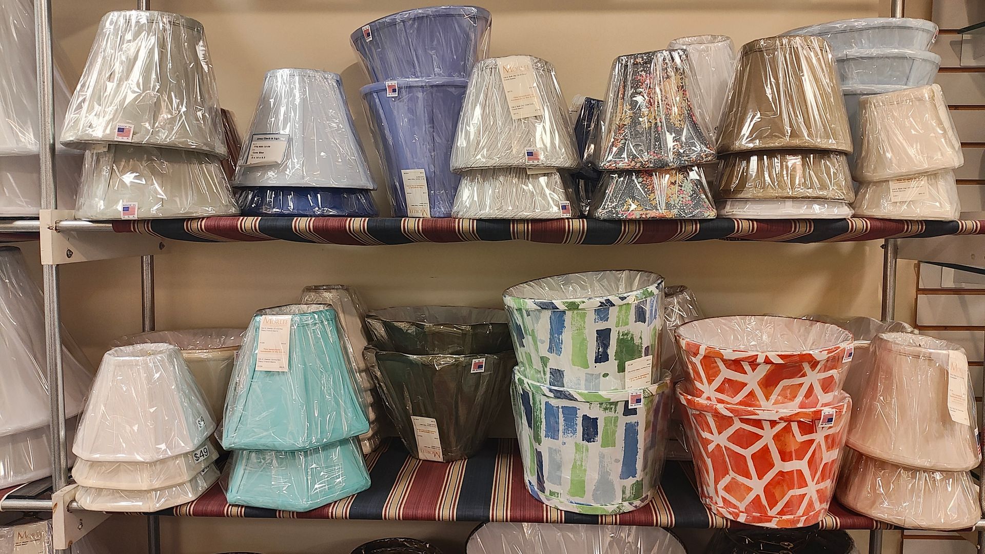 Shelves stacked with assorted patterned lampshades in white, blue, gold, and orange.
