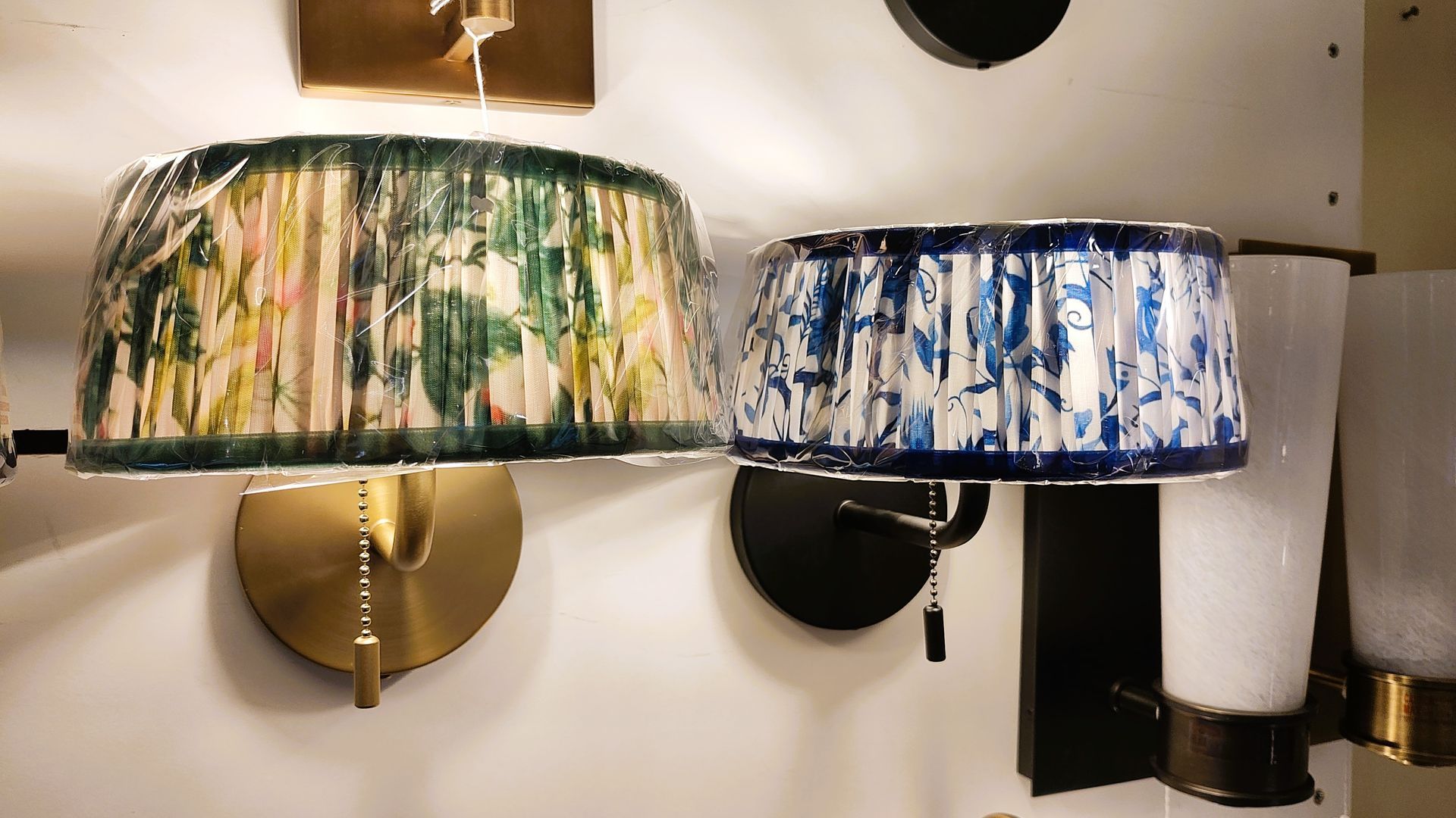 Two decorative wall sconces with pleated lampshades, one green-yellow and one blue-white. In Avon, CT
