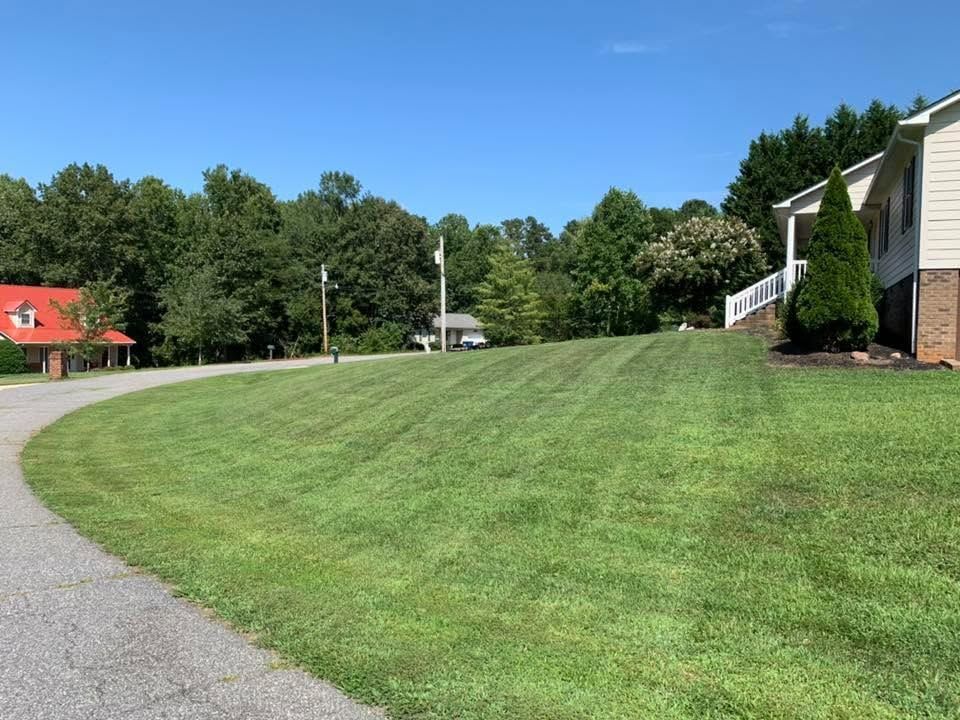 Mowed front lawn with edged walkway and seasonal plantings on a Catawba County property
