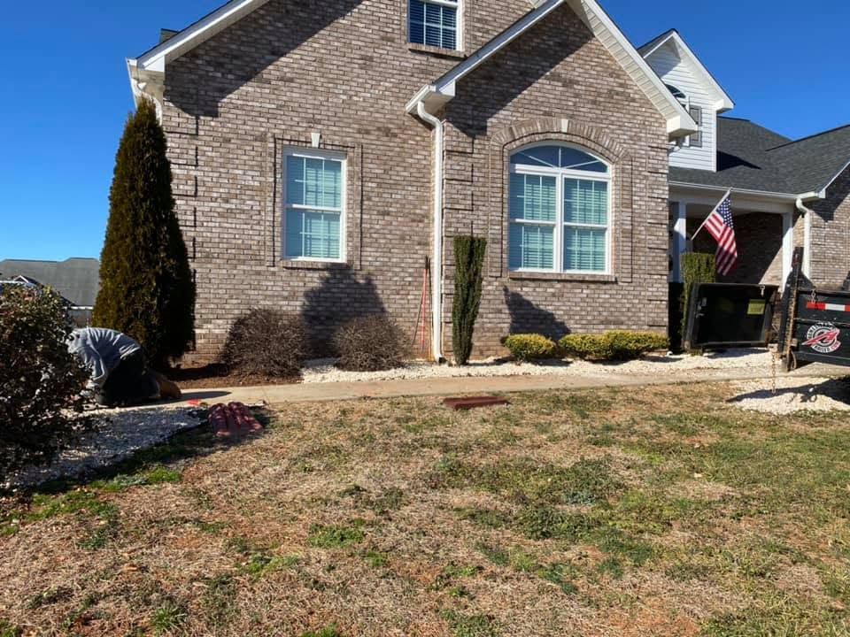 Stone suburban house with arched window, front lawn, and American flag by the porch.