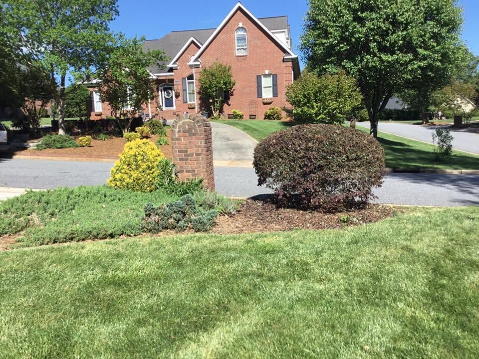 Mulched foundation bed with trimmed shrubs along a brick home on a Catawba County property