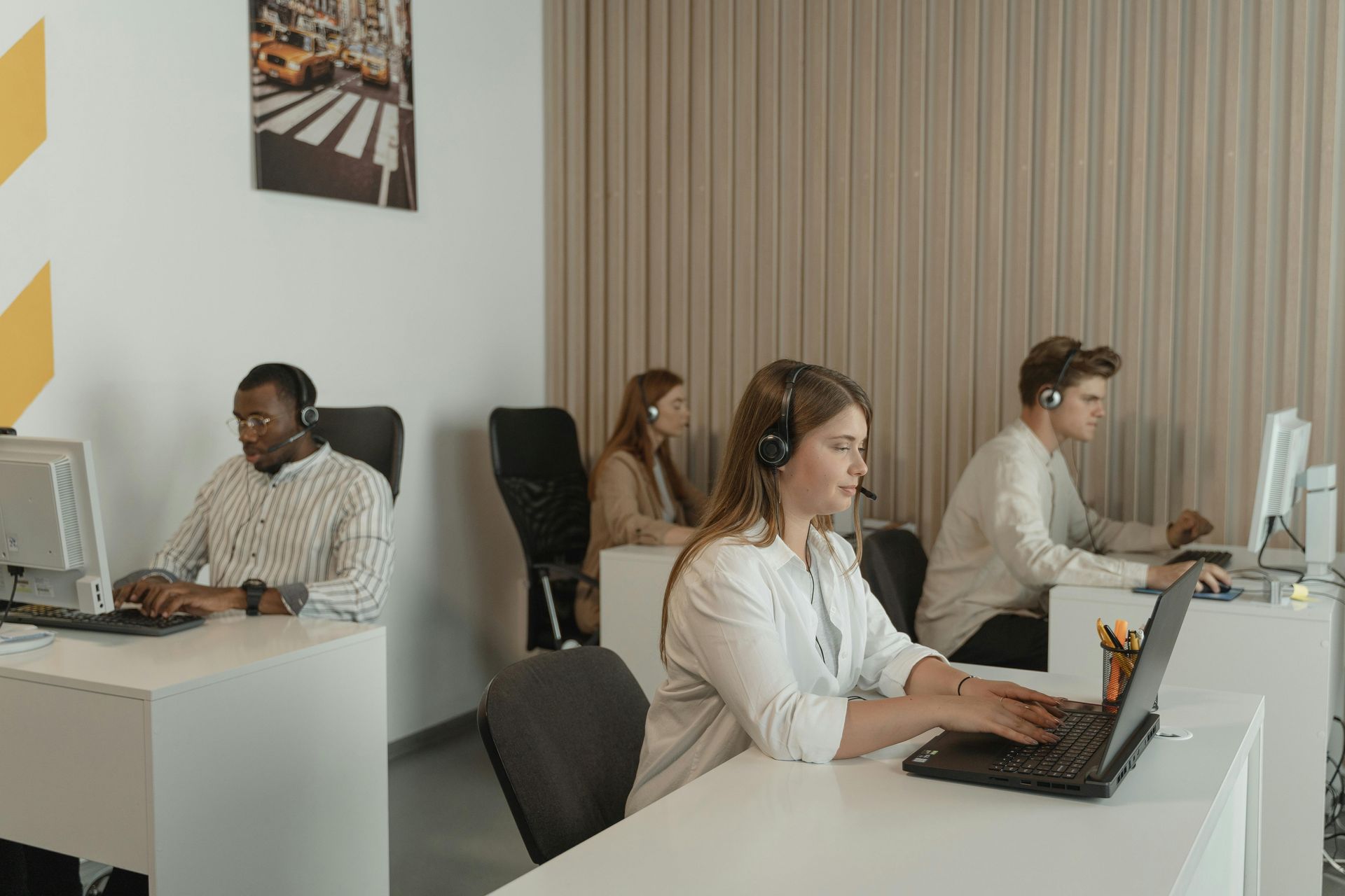 Personas que usan auriculares mientras trabajan con computadoras en un entorno de oficina.