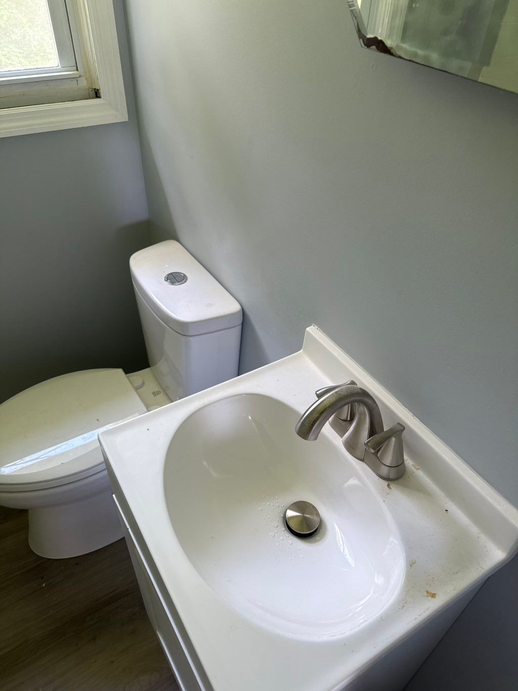 Bathroom with a white toilet and sink with a chrome faucet; gray walls.