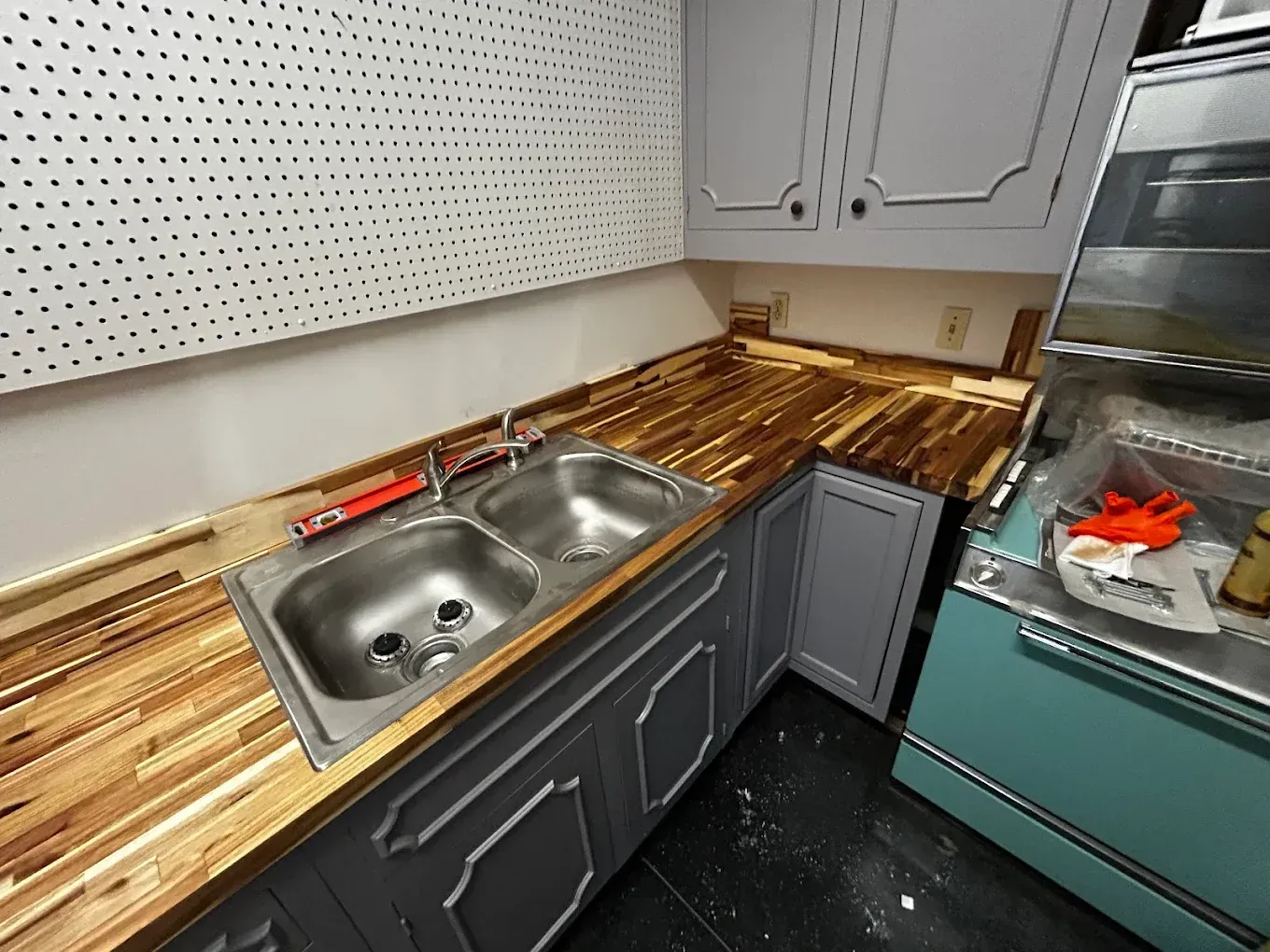 Kitchen with a double sink, wooden countertops, gray cabinets, and a teal refrigerator.