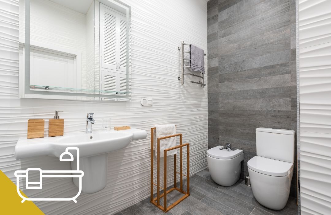 Modern bathroom with white sink, toilet, and gray tiled wall.