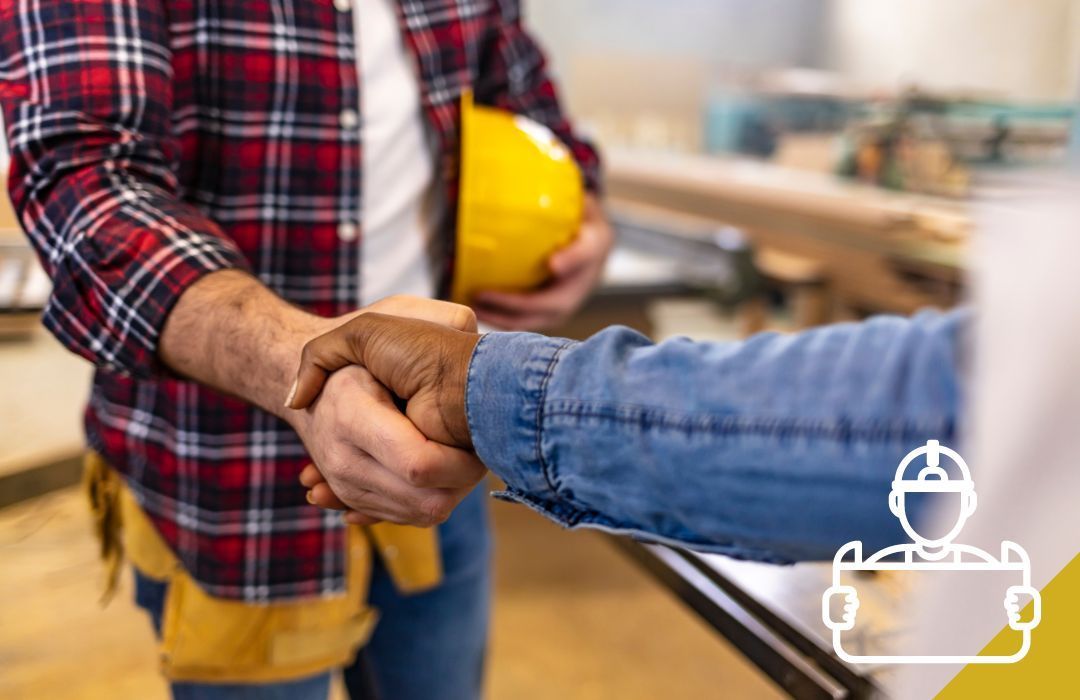 Two construction workers shaking hands; one holds a yellow hard hat.
