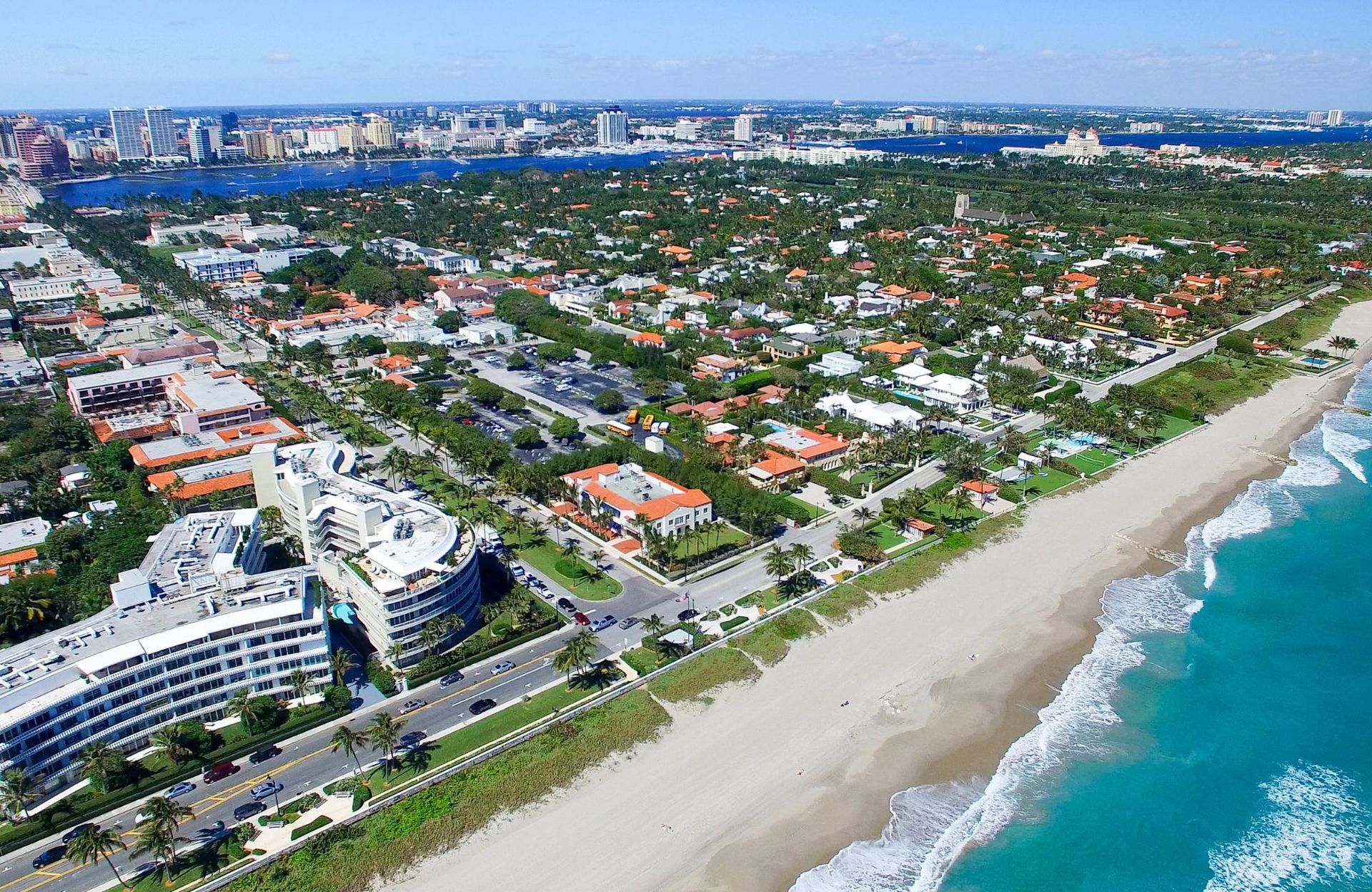 Aerial view of Palm Beach, Florida, with ocean and beach in the foreground, buildings, and foliage.