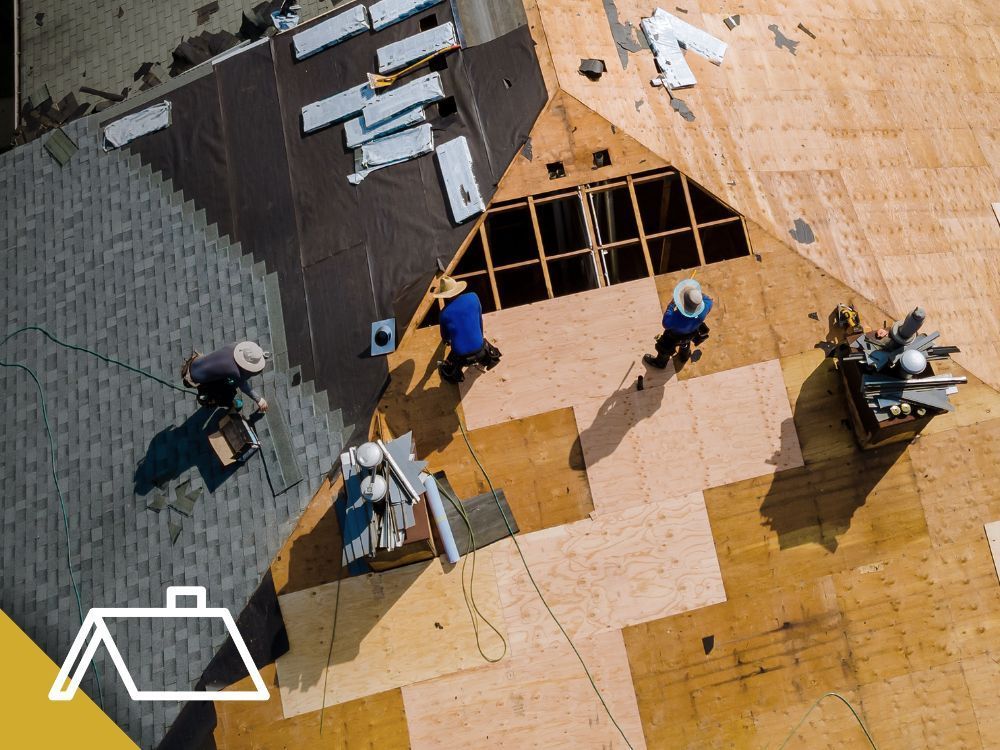 Roofers install new shingles on a house roof.
