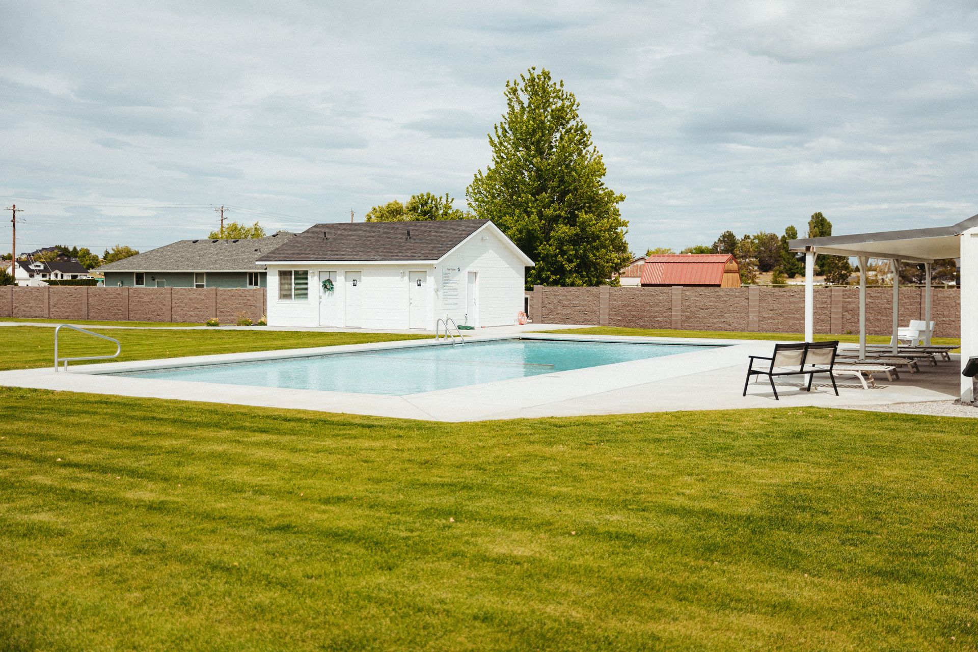 There is a large swimming pool in the middle of a lush green field.