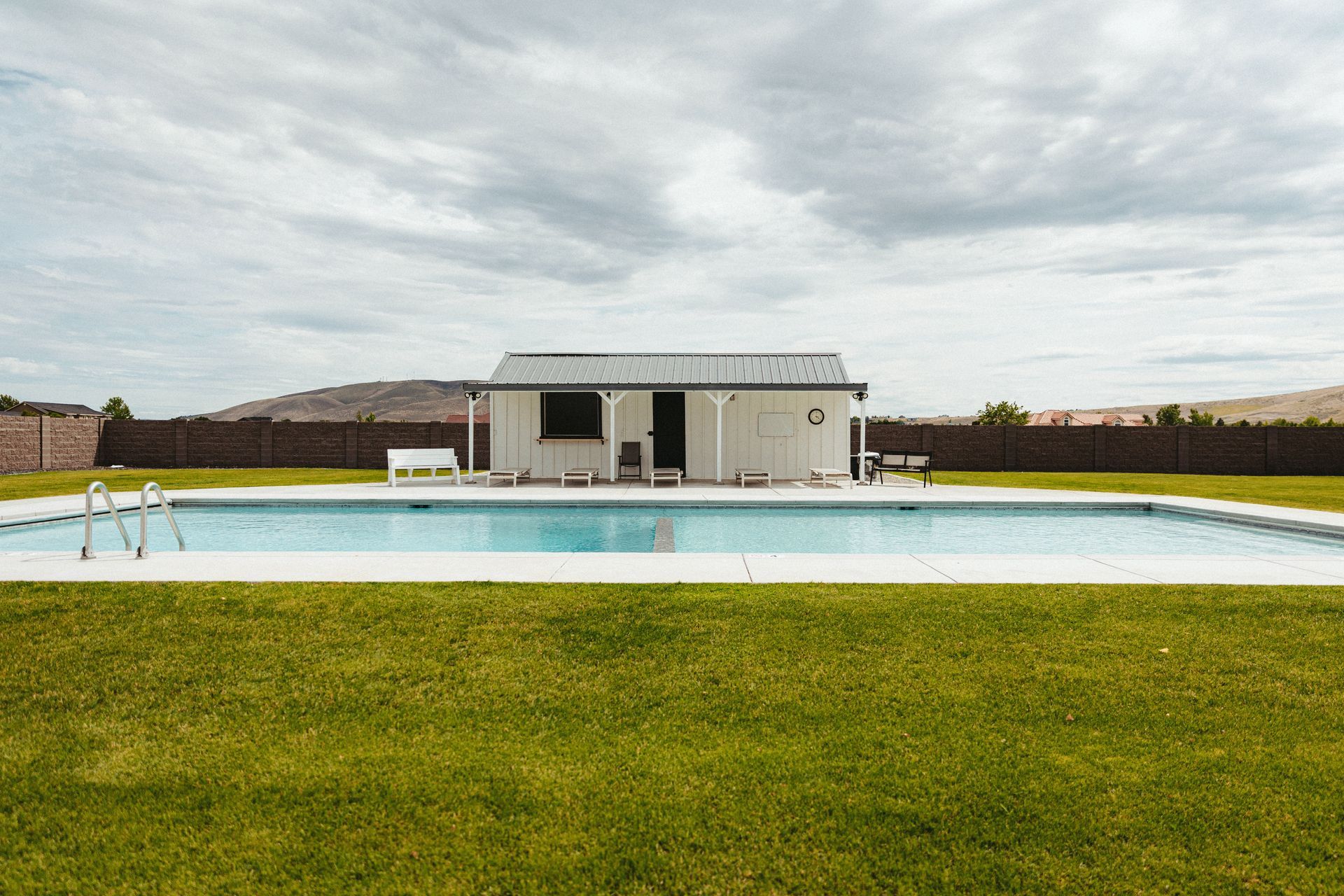 There is a large swimming pool in the middle of a lush green field.