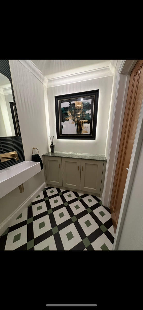 A modern bathroom with a geometric tile floor, grey cabinetry, a back-lit wall mirror, and a white floating vanity.
