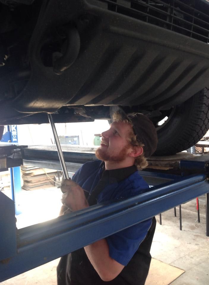 Mechanic Inspecting the Underside of a Vehicle on a Lift in a Workshop — Cooper's Auto Service Centre in Glen Innes, NSW