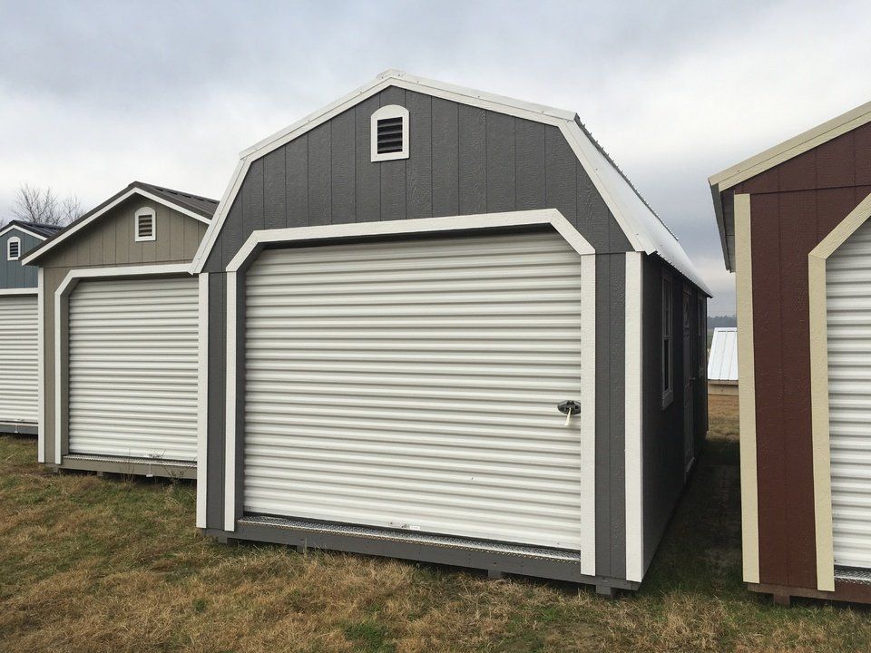 A row of sheds with roller doors are lined up in a field.