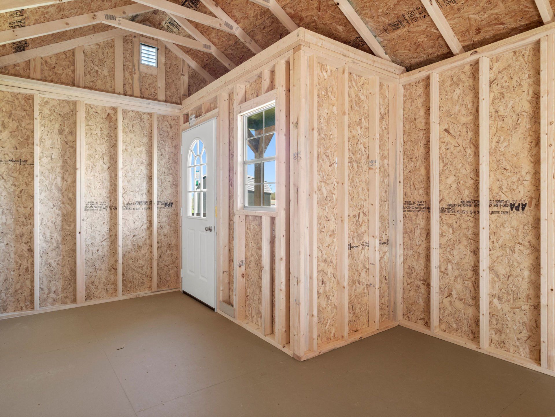 The inside of a wooden shed with a door and window.