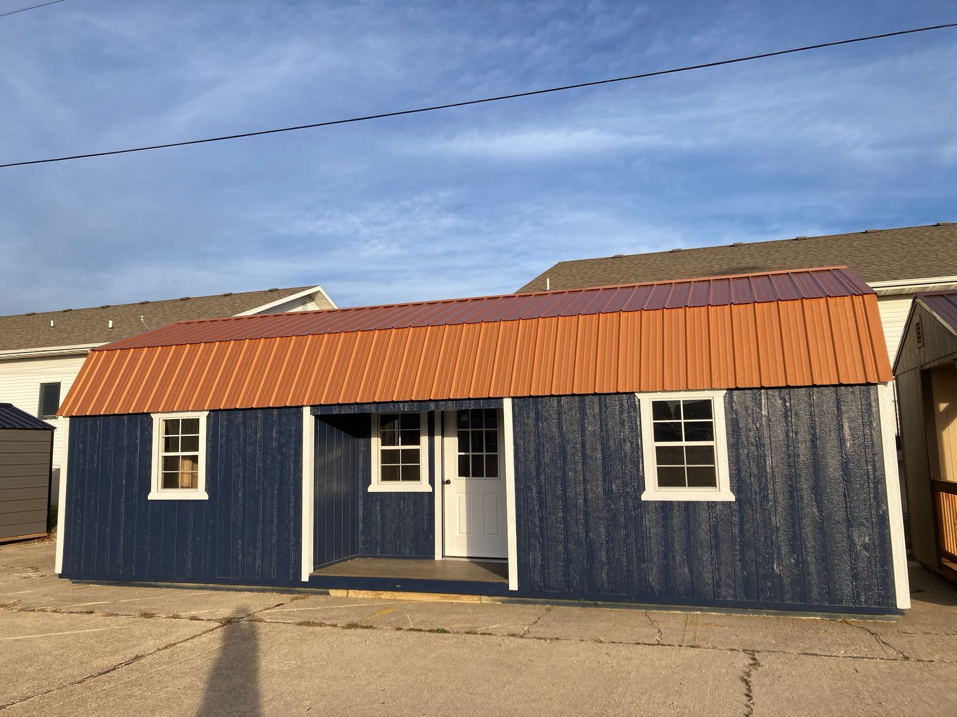 A blue shed with a copper roof and white windows