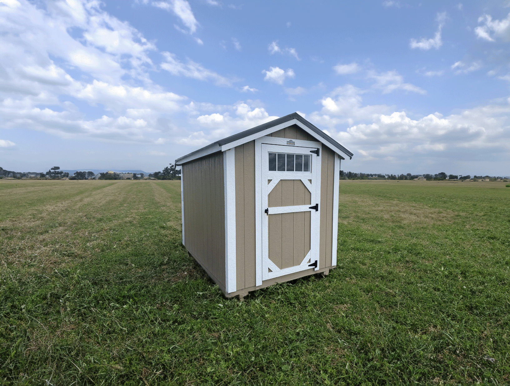 A small orange shed is sitting on a sandy beach near the water.