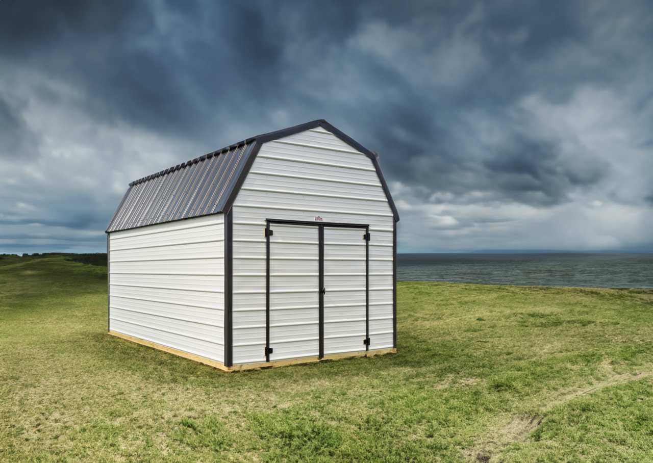 Small white shed with gray roof in a grassy field under a cloudy sky