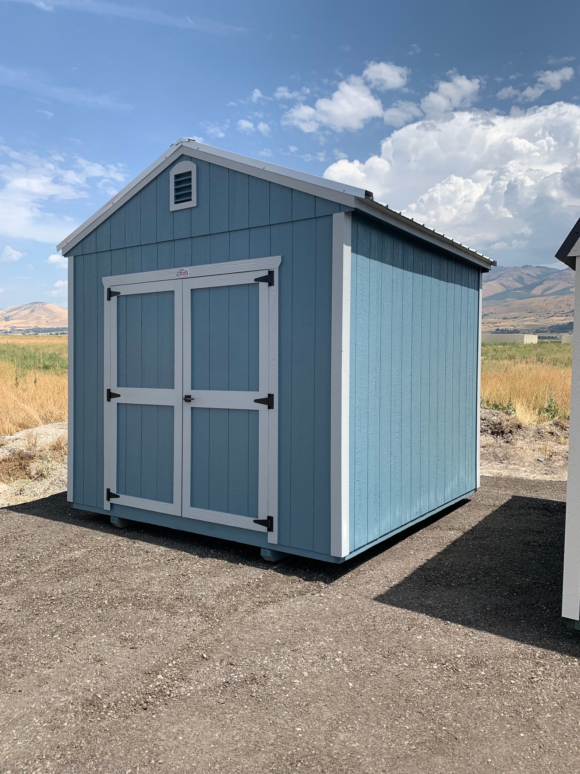 A small shed is sitting in the middle of a grassy field.