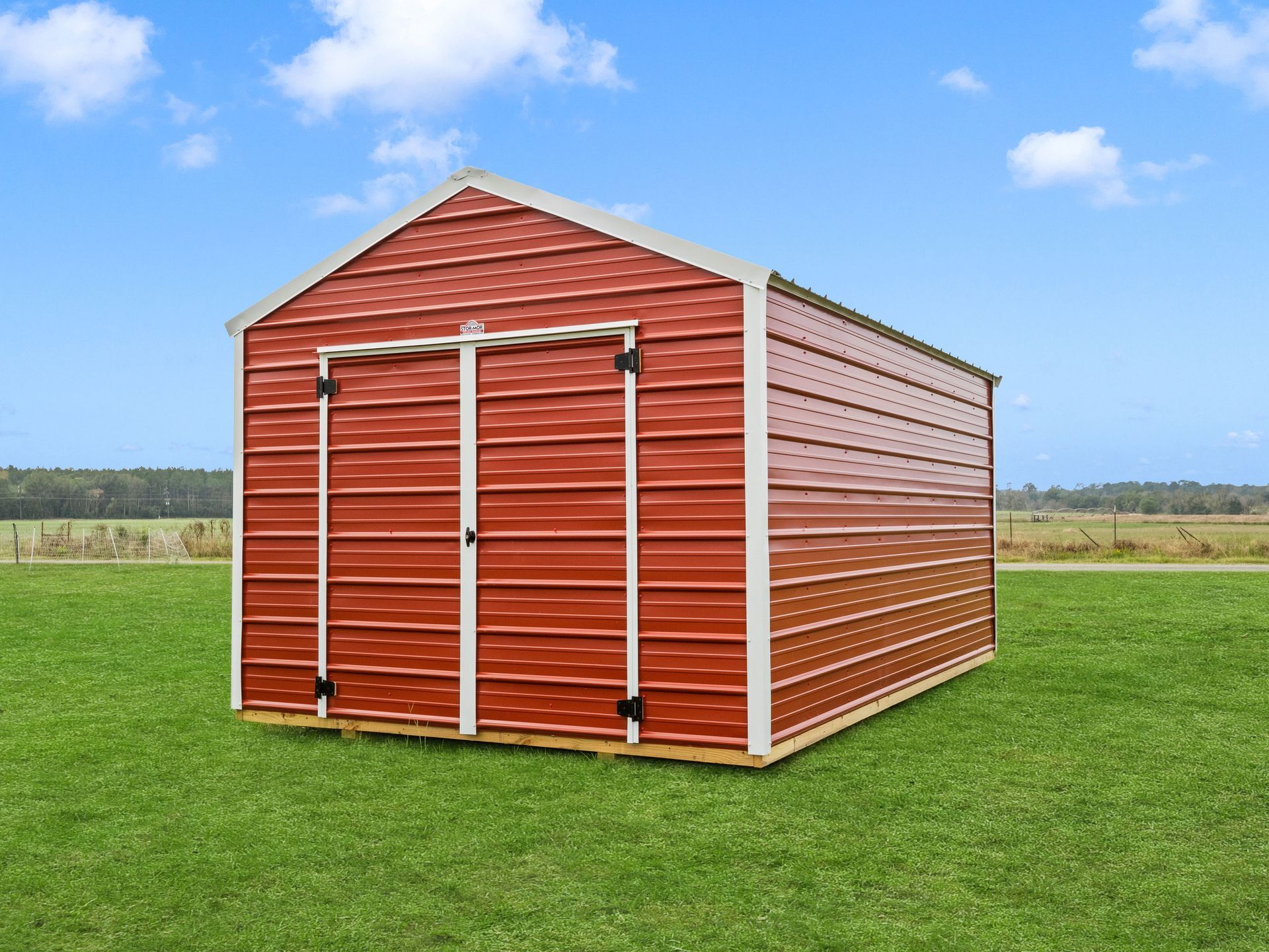 A grey metal shed is sitting in the middle of a grassy field.