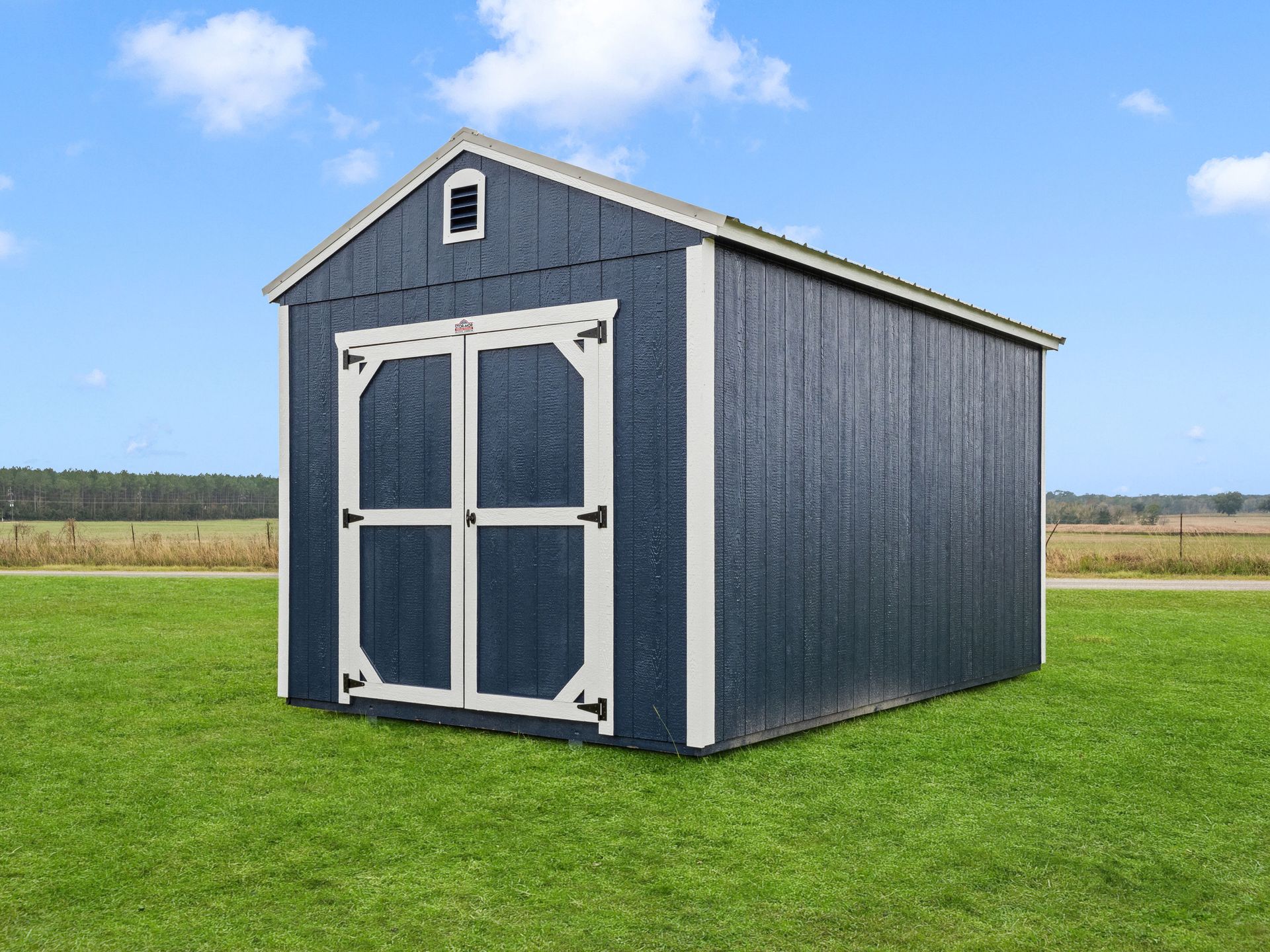 A blue and white shed is sitting on top of a lush green field.