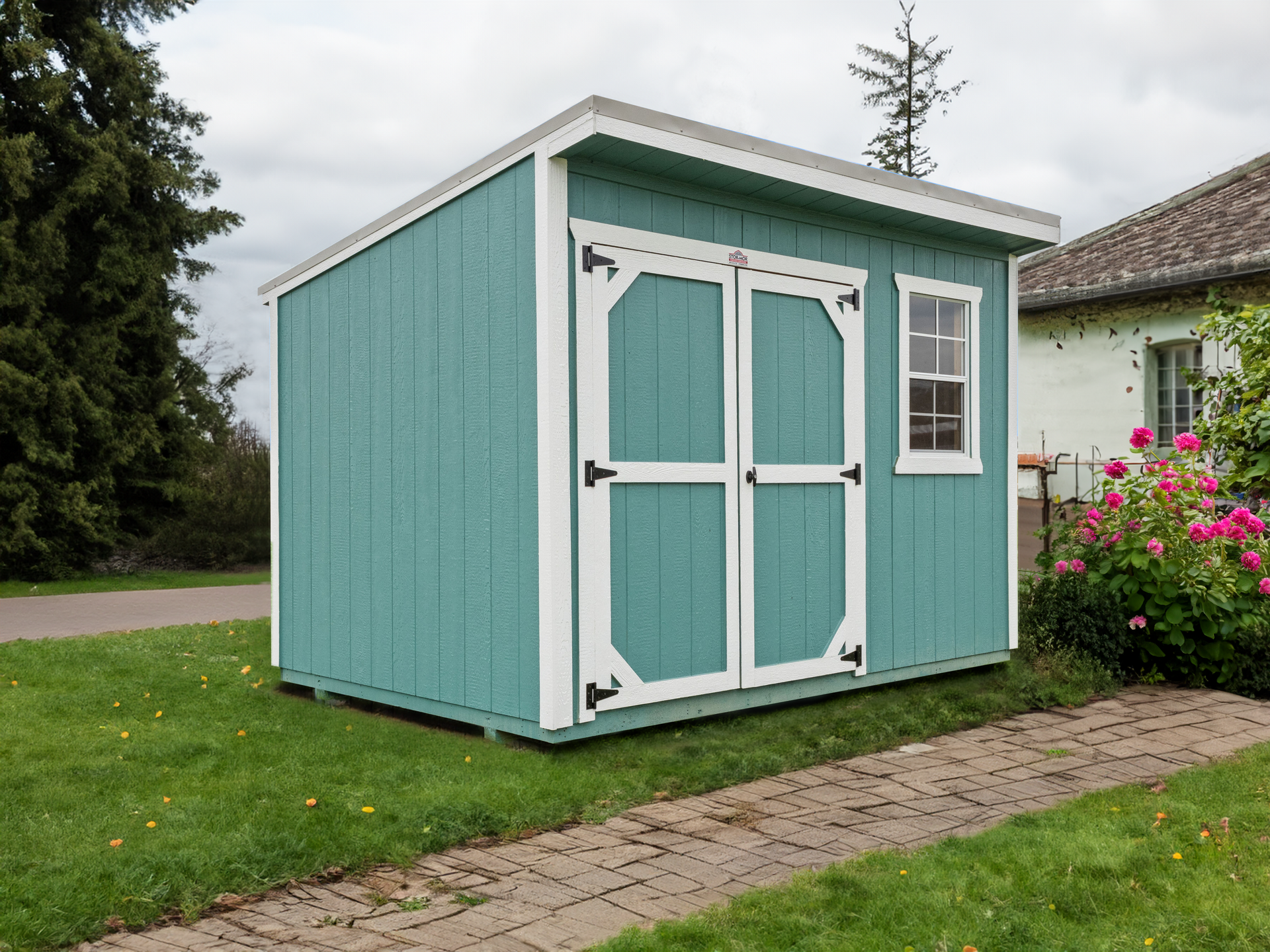 A blue and white shed is sitting on top of a lush green lawn next to a house.