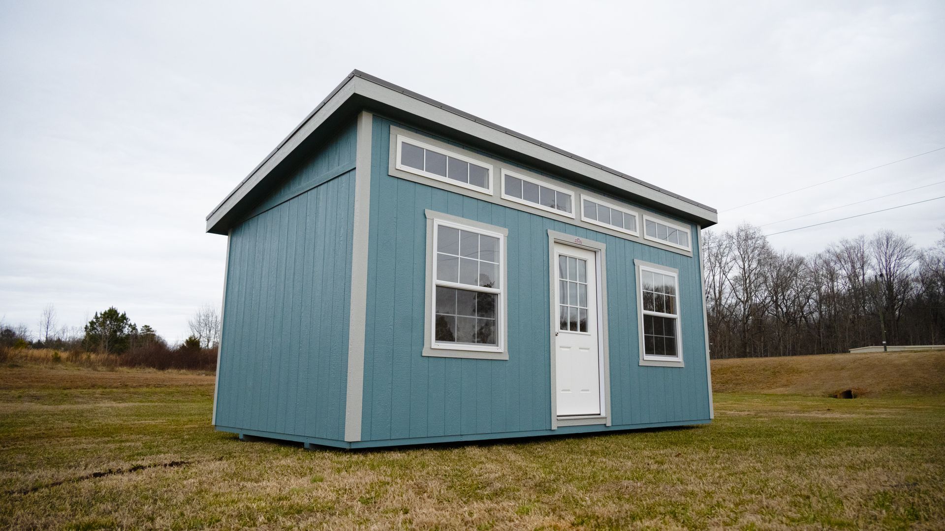 A small blue shed with a white door and windows