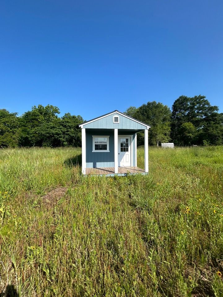 A cabin is sitting in the middle of a grassy field.