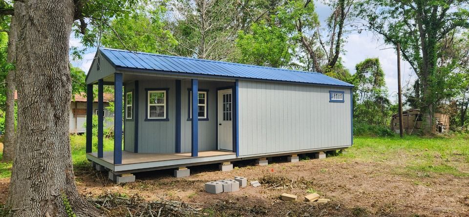 A deluxe cabin with a blue roof is sitting in the middle of a field.