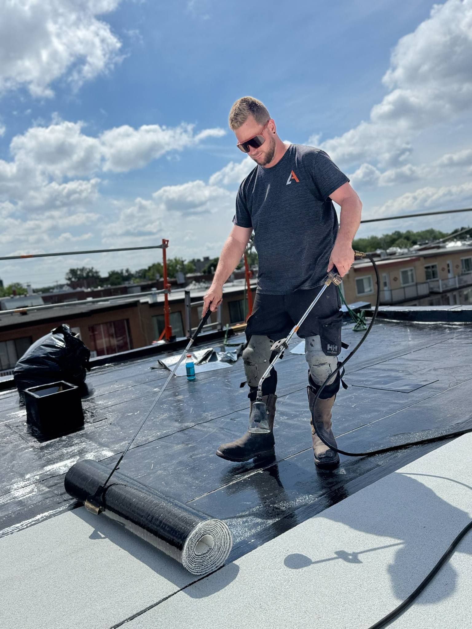 Un ouvrier inspecte la membrane d'étanchéité du toit sous un ciel nuageux.