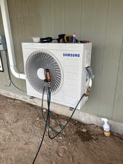 A samsung air conditioner is being installed on the side of a building.