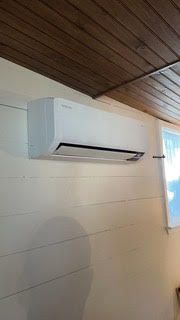 A white air conditioner is hanging on a wall next to a window.