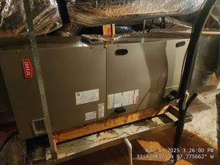 A large air conditioner is sitting on top of a wooden shelf in a basement.