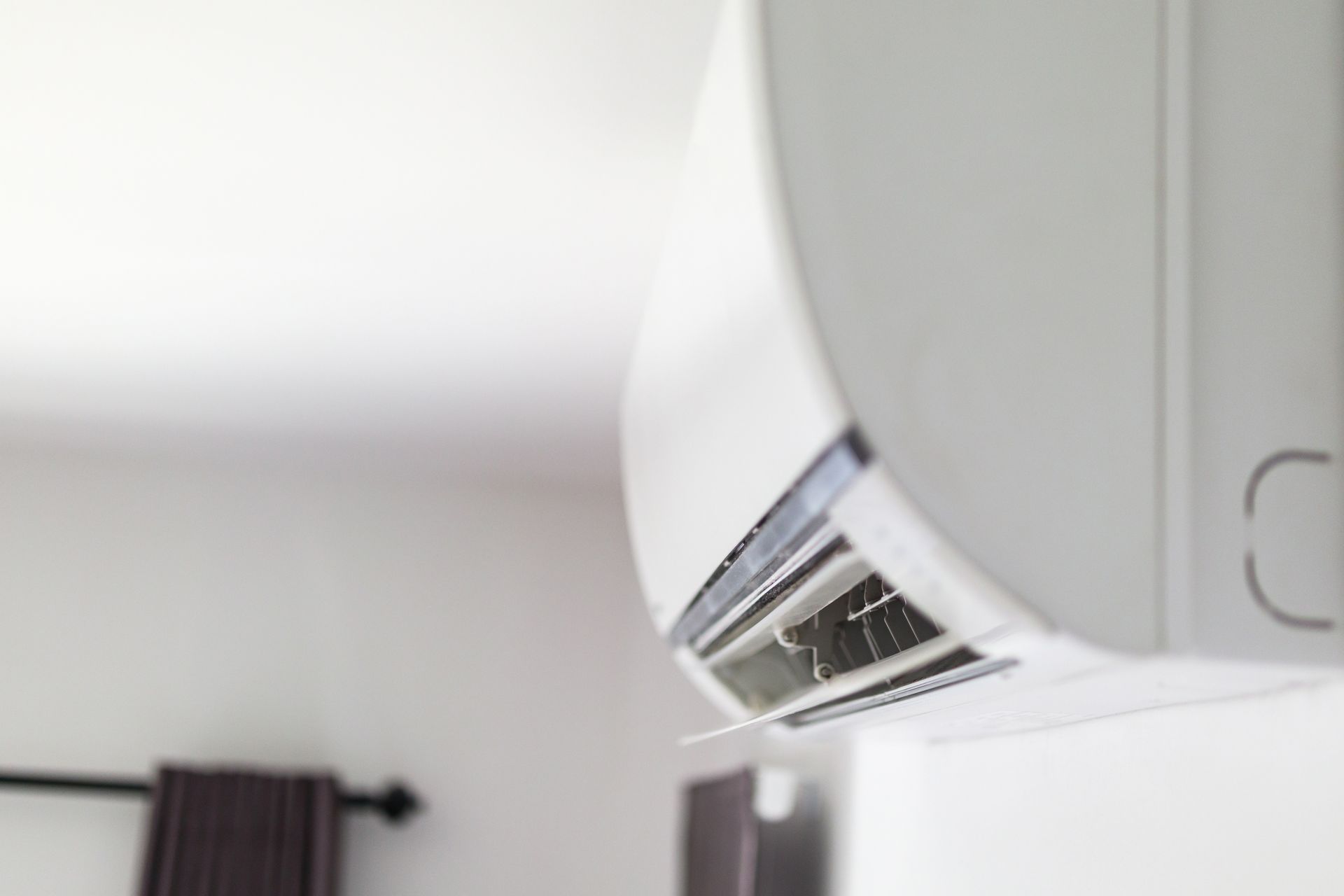 A white air conditioner is hanging from the ceiling in a room.
