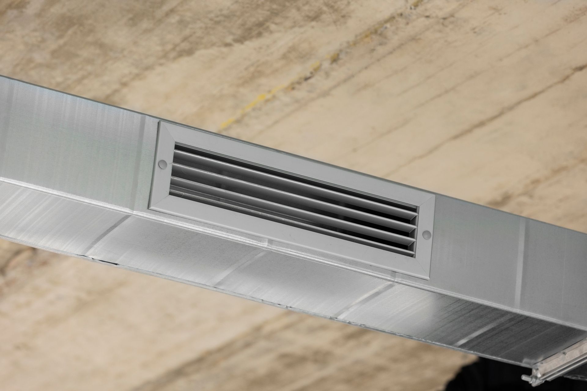 A close up of a metal duct with a vent on the ceiling.