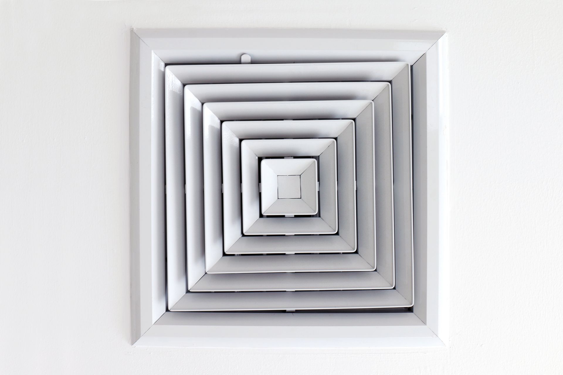 A white square air vent on a white wall.