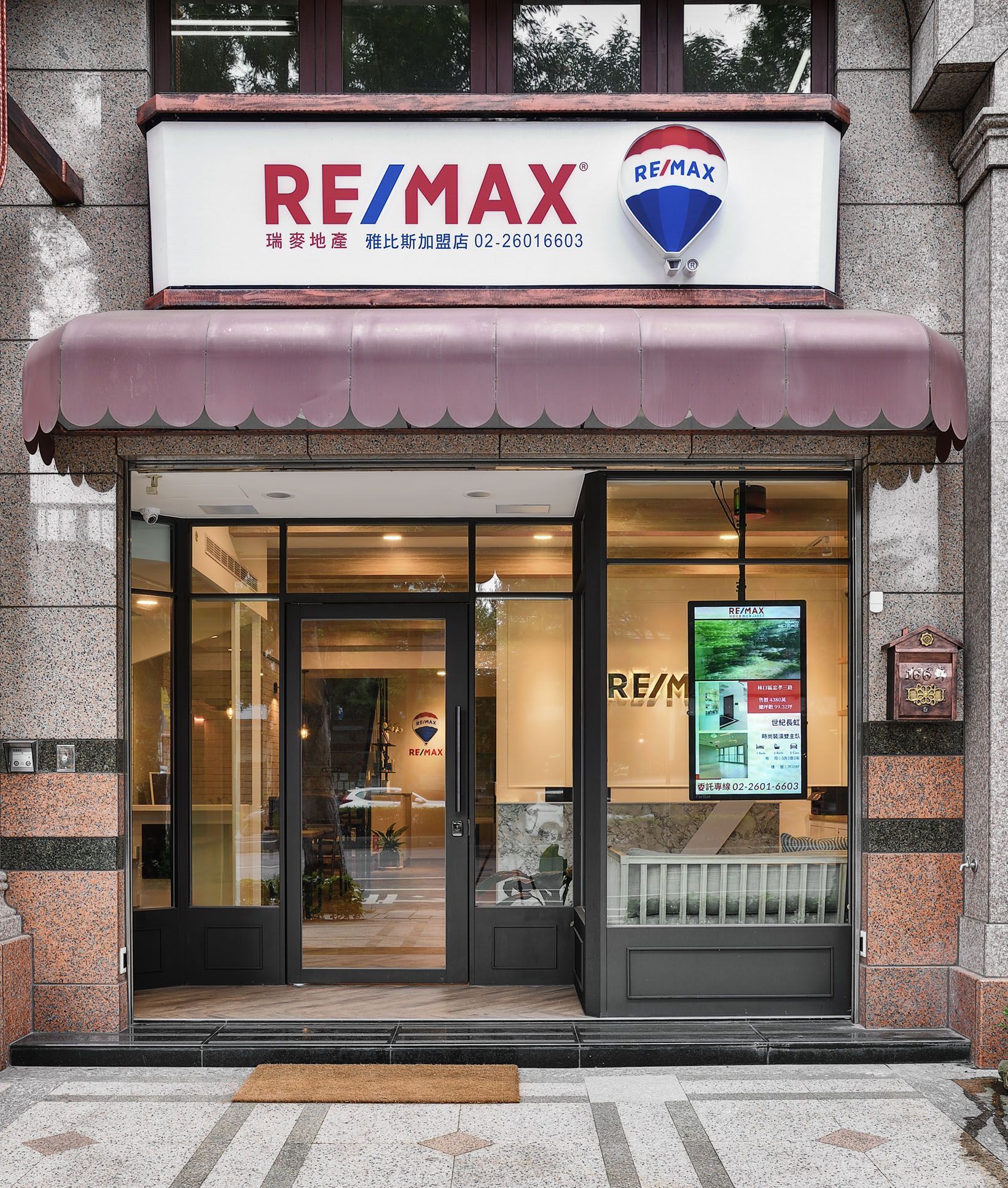 RE/MAX 房地產辦公室店面,附遮陽棚、玻璃門和招牌。
