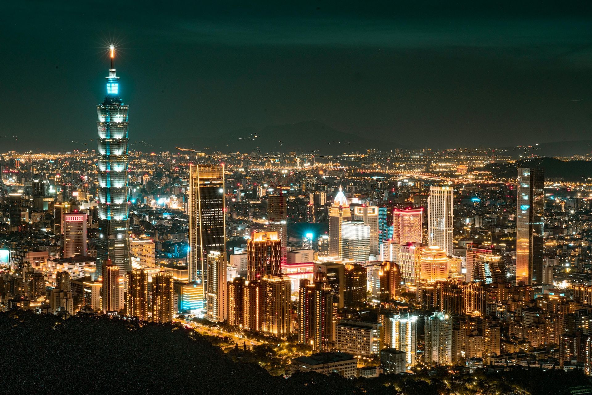 台北市夜景，台北101大樓亮起藍色燈光，其他建築則亮起金色和白色燈光。