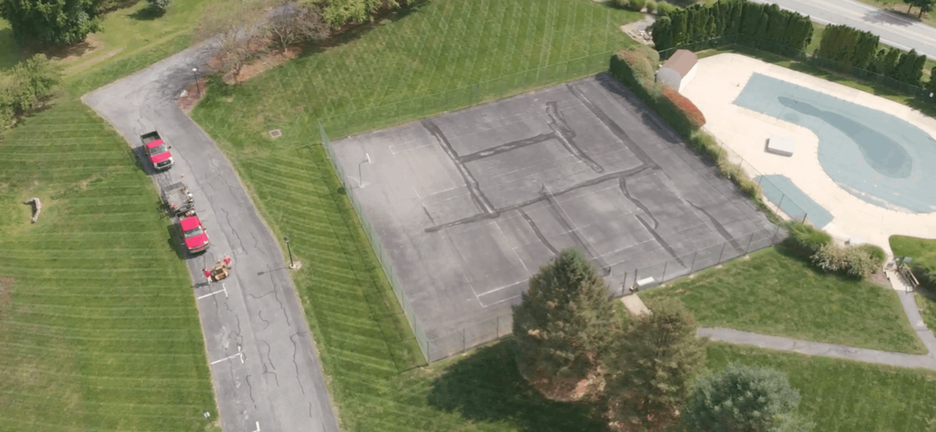 A lush green lawn with a brick building in the background and a large field in the background.