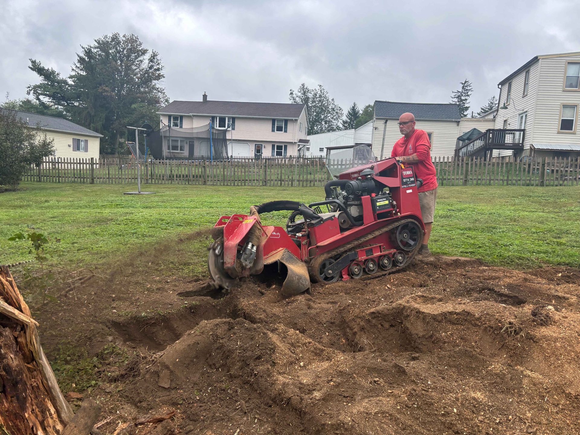 A stump grinder is cutting a tree stump in a yard.