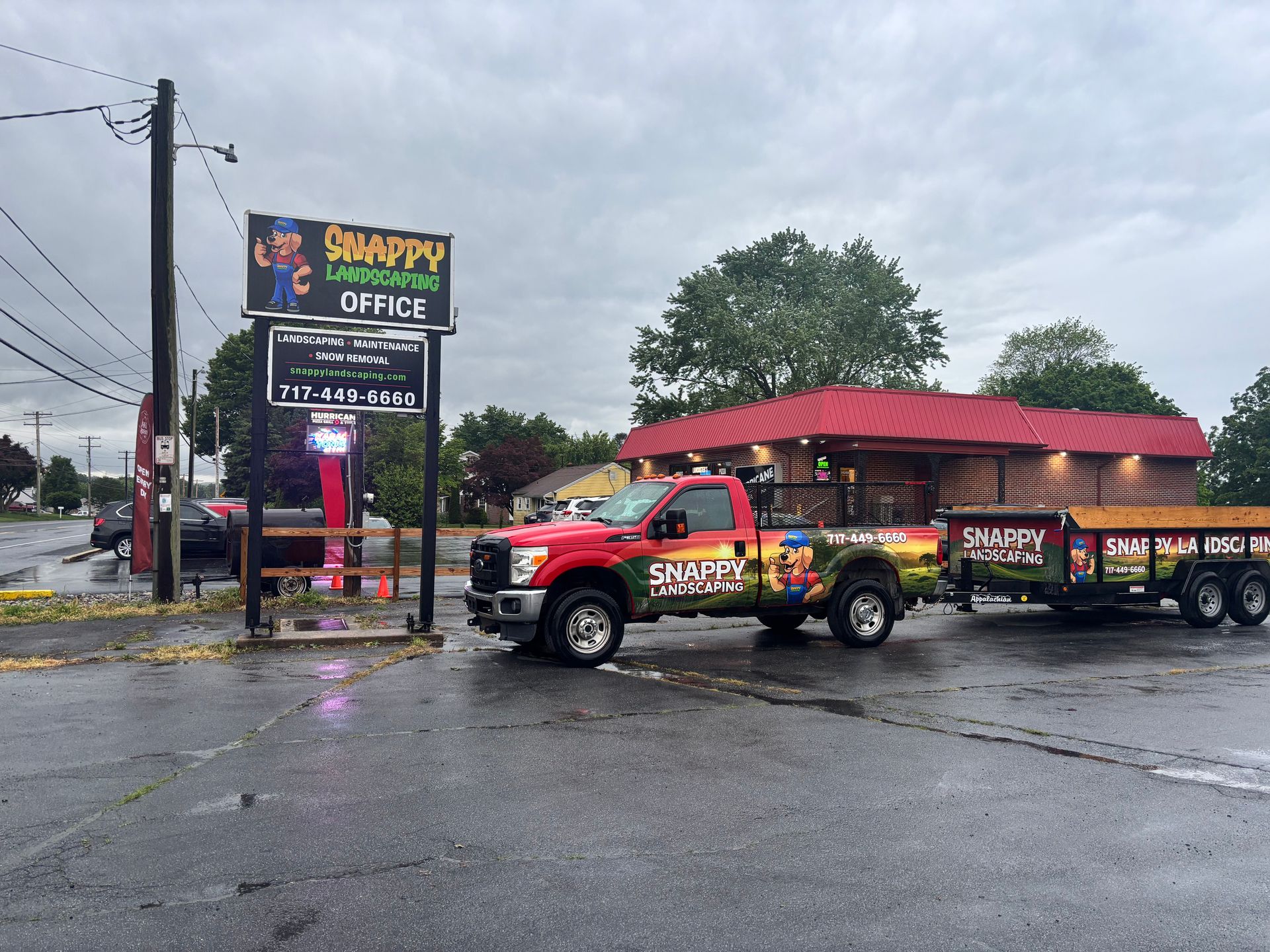 Outdoor Projects Red Shanty office towing a trailer in a wet parking lot by a roadside sign on a rainy day
