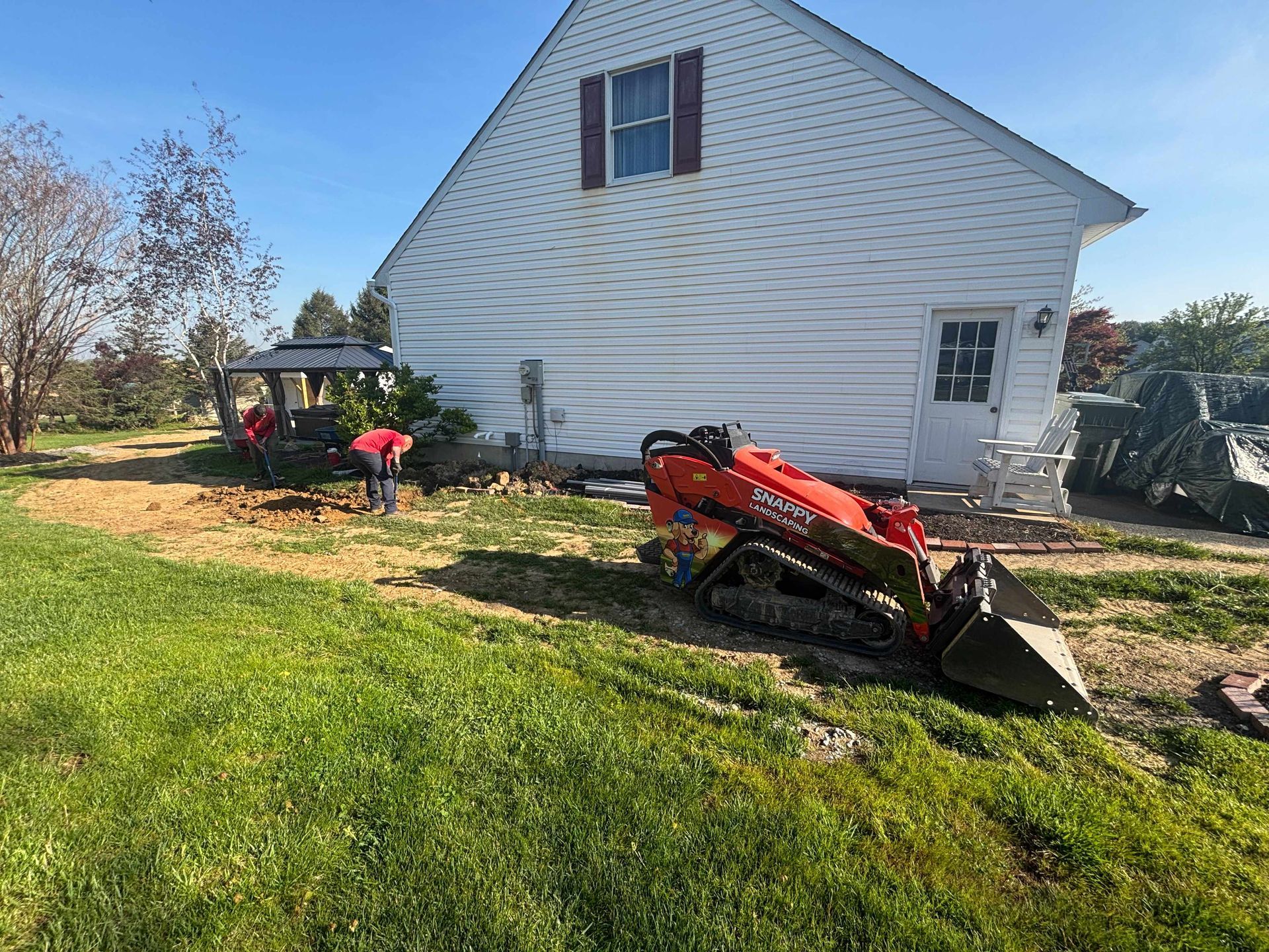 White house with a red tractor and a person in a red shirt working in the yard