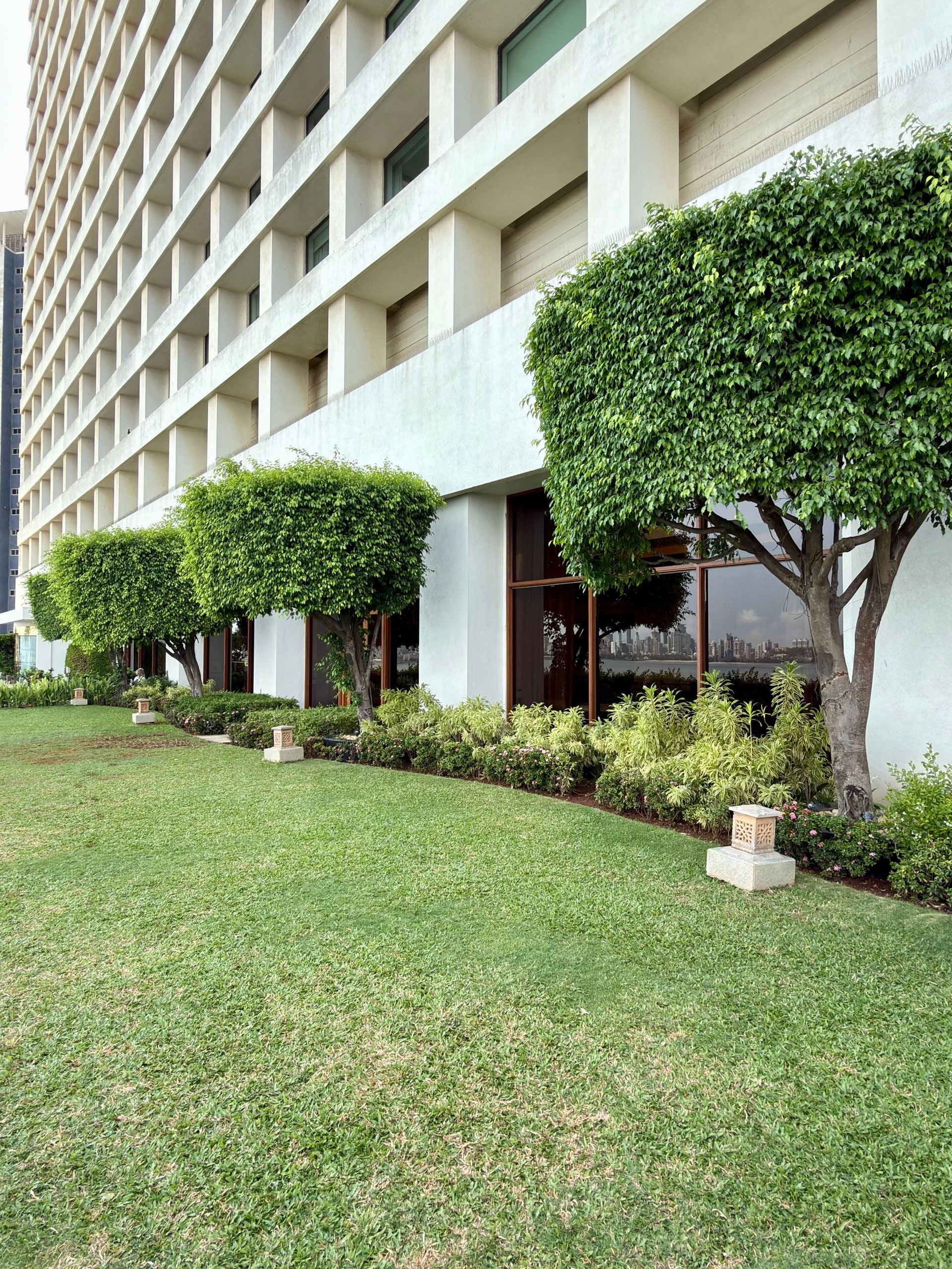Modern hotel exterior with manicured lawn and neatly trimmed trees along the building façade