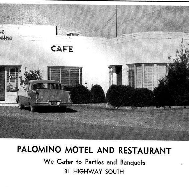 Black-and-white view of Palomino Motel and Restaurant with a parked car and café sign.
