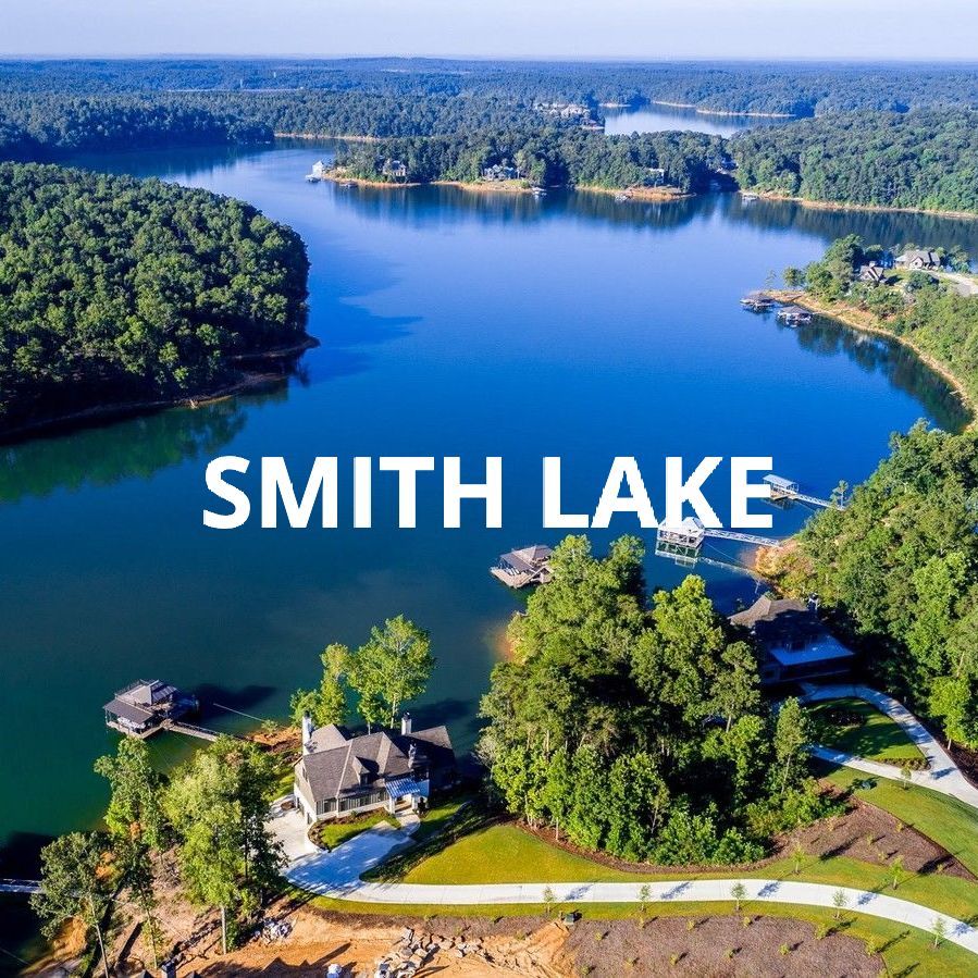 Aerial view of Smith Lake with blue water, tree-lined shores, and a lakeside road with homes.