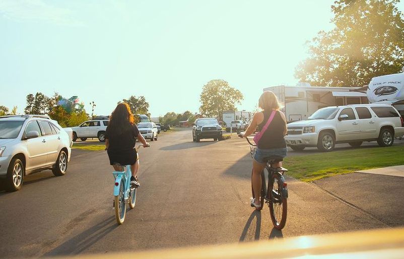 Two women are riding bicycles down a street.