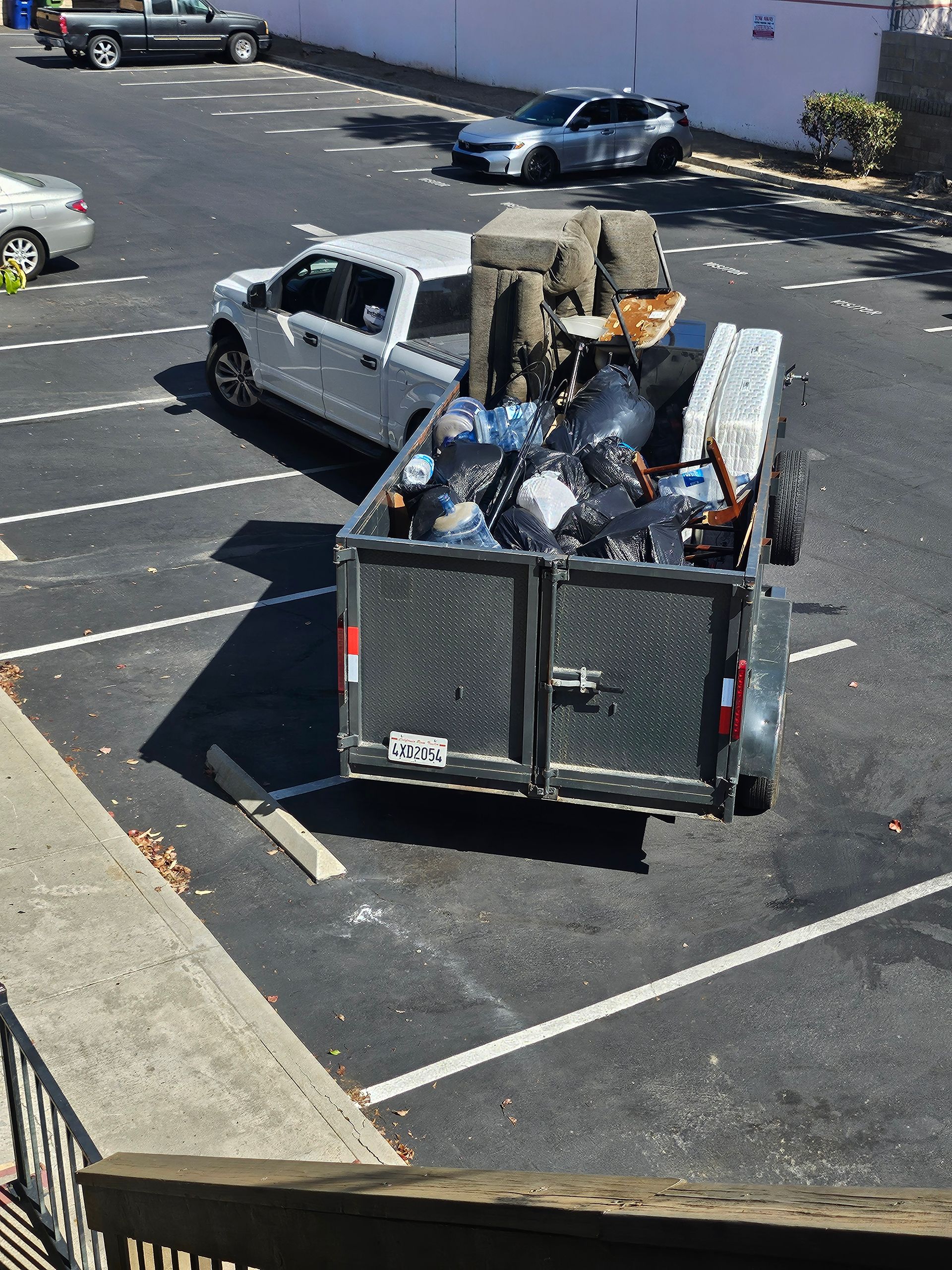 Worker loading debris into a truck bed in a parking lot