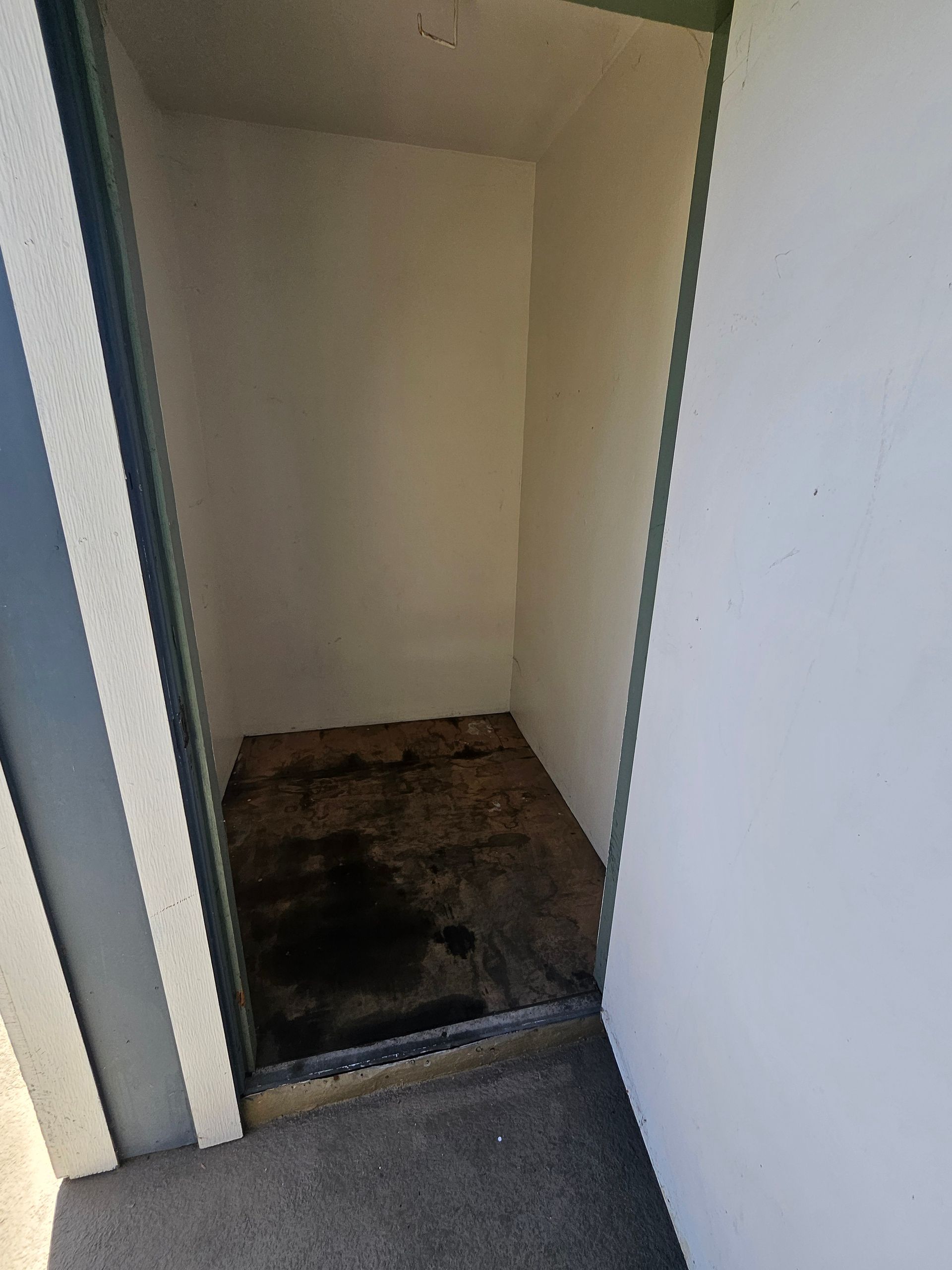 Empty closet with a dark stained floor and white walls.