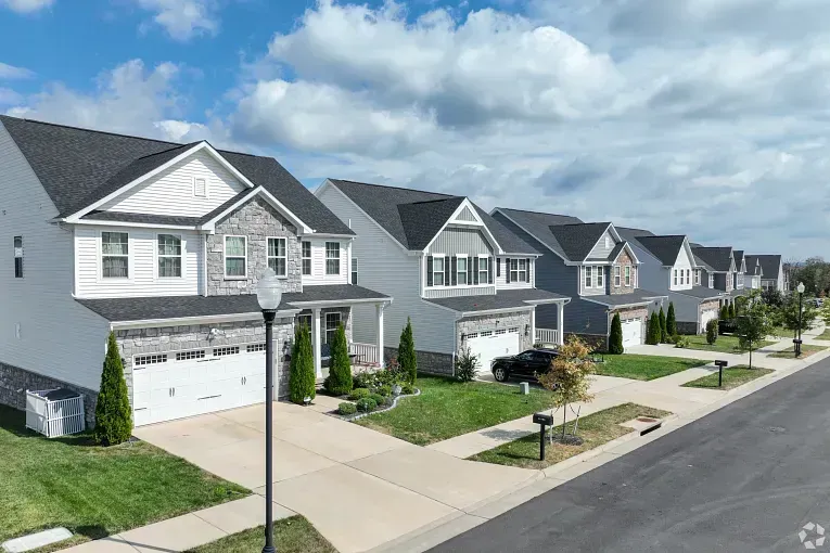 Row of new suburban houses with driveways and a quiet street under a cloudy sky