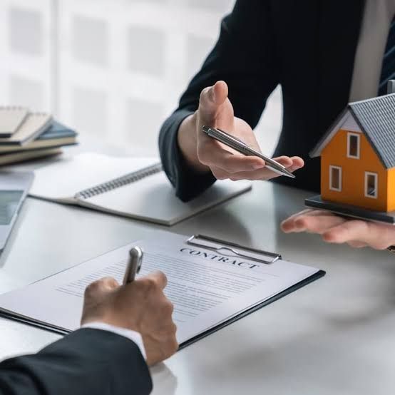 Business meeting signing a real estate contract beside a small house model