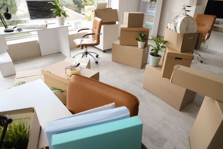 Cardboard boxes and office furniture in a bright, empty room during a move